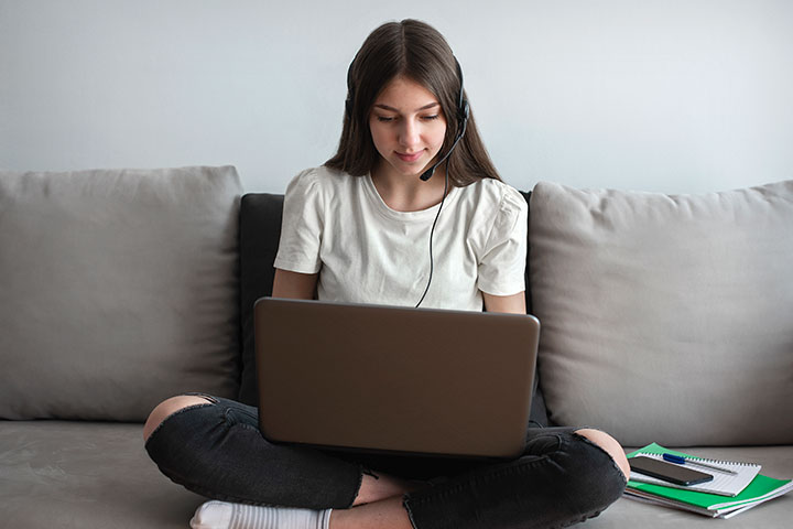 Jovem com fone de ouvido olhando para a tela do computador
